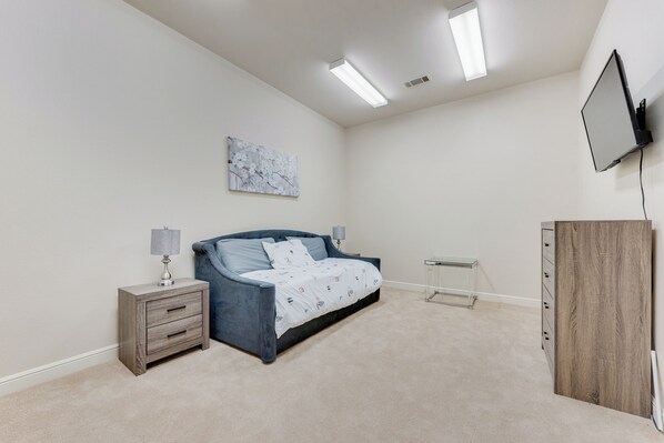 Ein Schlafzimmer mit einem Bett, Nachttischen, einem Fernseher und einem Bild an der Wand.