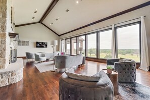 A spacious living room with a stone fireplace, large windows, and modern furniture. - DEN105 -Private Ranch Compound | Pool, Gym & Court (Denton)