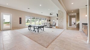 A spacious room with a large table, a stone accent wall, and a view through large windows.