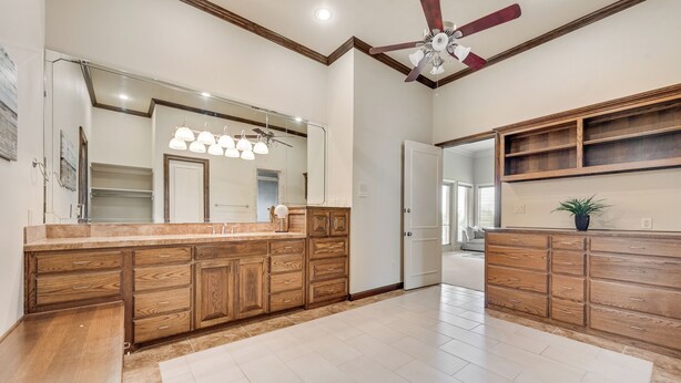 A spacious bathroom with a wooden vanity, a large mirror, and a ceiling fan.