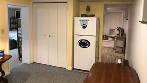 Ett kompakt kök med ett vitt kylskåp, ett träbord och ett stängt skåp.