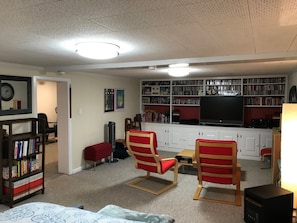 Ein Wohnzimmer mit Bücherregal, Fernseher und zwei roten Sesseln.