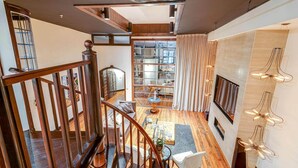 A spacious living area with a wooden staircase, a fireplace, and a modern light fixture. - Historic Riverfront Condo for 8, Near Broadway! (Nashville)