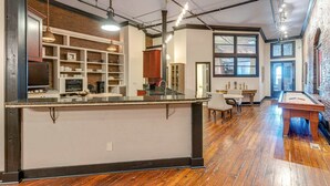 A spacious kitchen with a central island, built-in shelves, and a dining area with a table and chairs. - Historic Riverfront Condo for 8, Near Broadway! (Nashville)