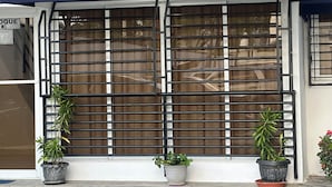 Une façade d’immeuble avec un auvent bleu, des fenêtres grillagées et des plantes en pot au niveau du rez-de-chaussée.