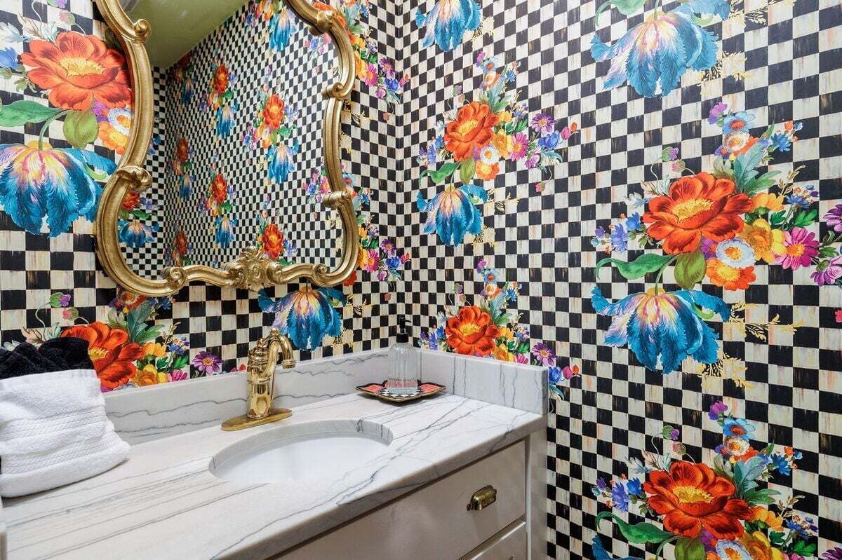 Een badkamer met een zwart-wit geruite vloer, een marmeren wastafel en een spiegel met gouden lijst.