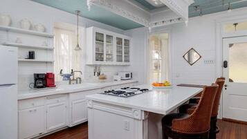 A kitchen with white cabinetry, a central island, and wicker chairs.