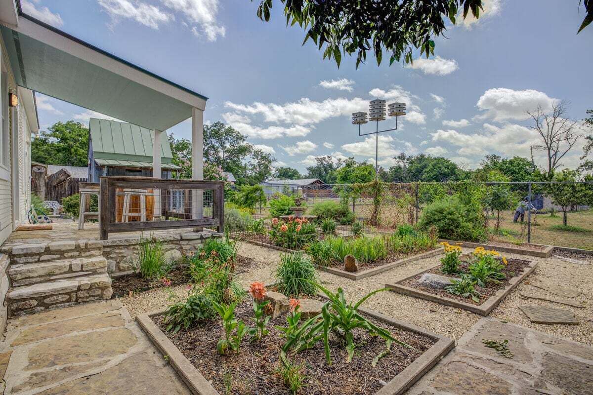 A garden with raised beds, a stone pathway, and a covered patio area.