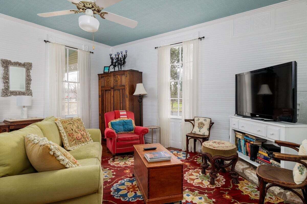 A living room with a sofa, armchair, coffee table, TV, and bookshelves.