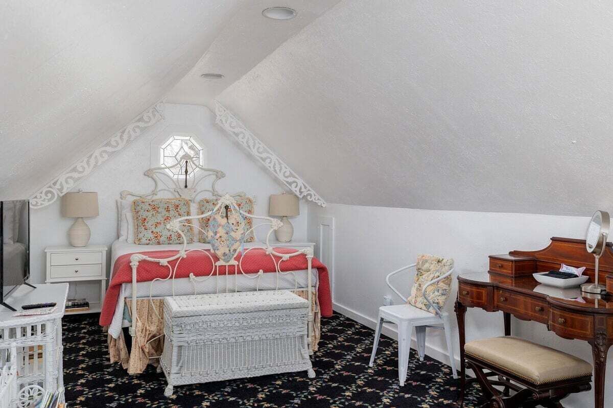 A bedroom with a bed, a dresser, a chair, a small table, and a window.