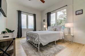 A bedroom with a bed, bedside tables, a desk, and a window with curtains. - Eagles Nest View of Lake Buchanan - 2BR With Hot Tub & Gorgeous Views (Burnet)
