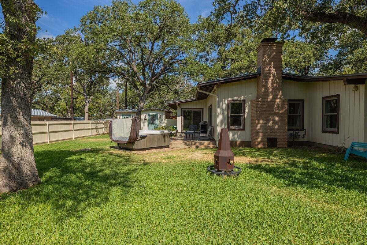 A house with a covered patio, a brick chimney, and a lawn.