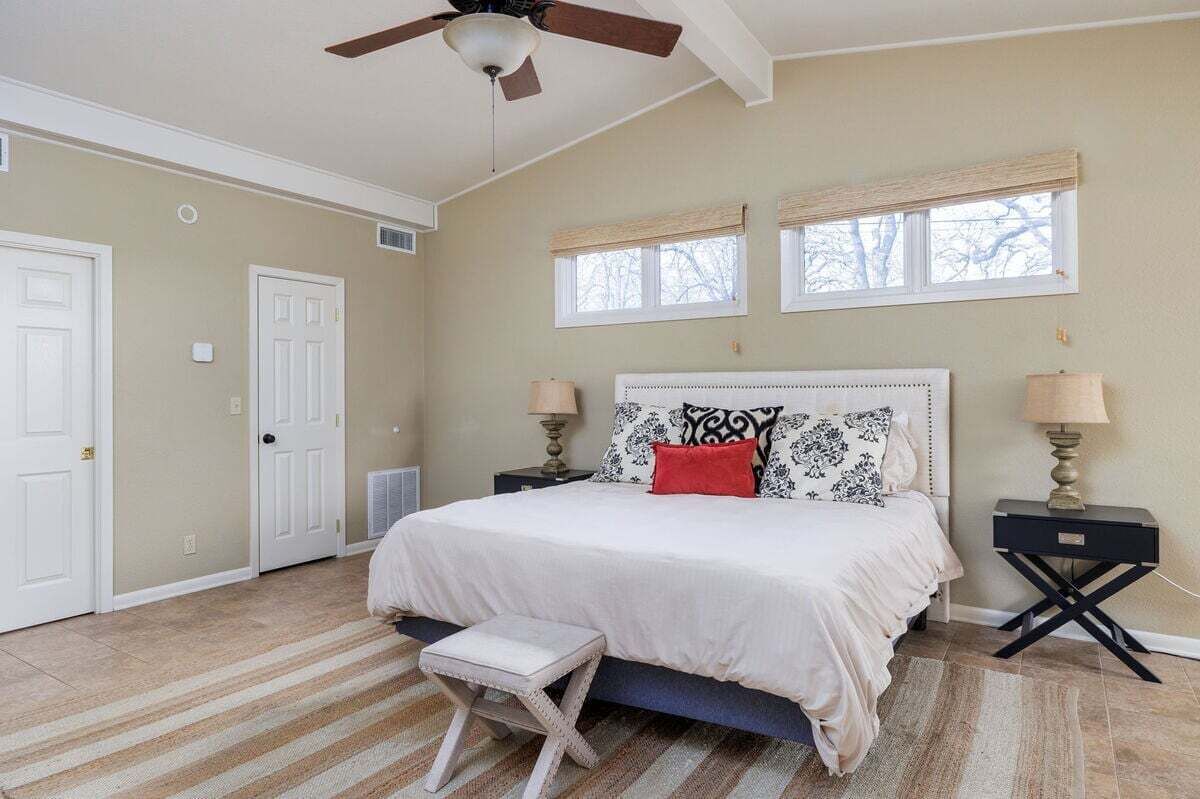 A bedroom with a bed, two bedside tables, a ceiling fan, and a window.