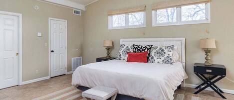 A bedroom with a bed, two bedside tables, a ceiling fan, and a window.