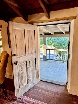 A wooden door leading to an outdoor deck with a railing. - Historic Rumpel Kammer Compound (Fredericksburg)