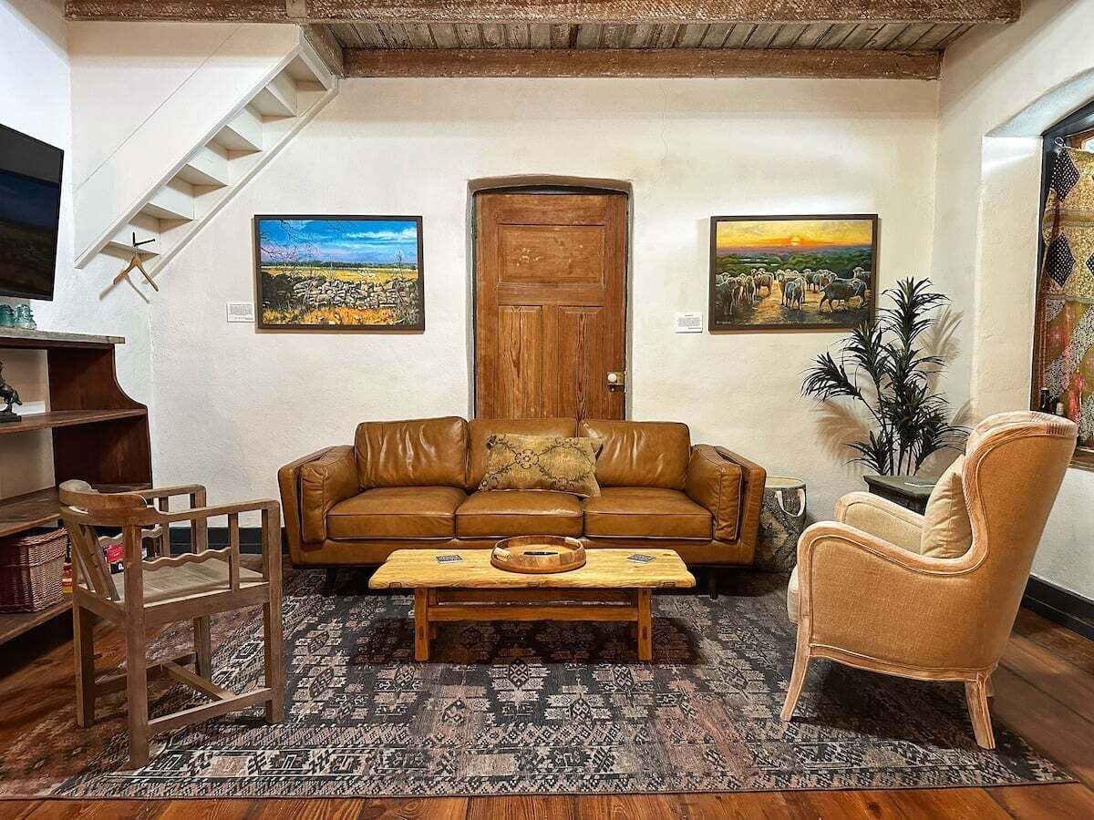 A living room with a sofa, armchair, coffee table, and a staircase.