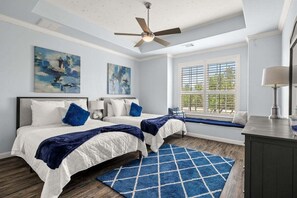 A bedroom with two beds, a ceiling fan, a window with blinds, and artwork on the walls. - Hill Country Escape-670 Heather Hills (Dripping Springs)