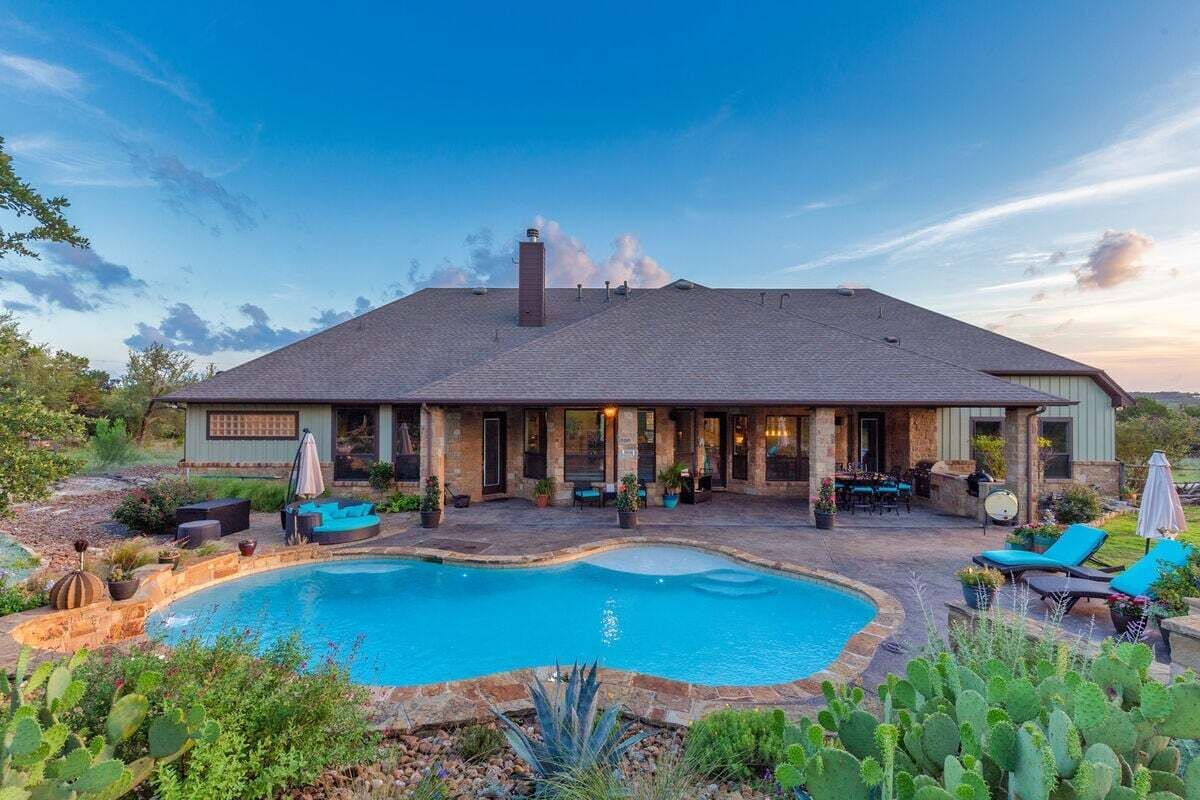 Ein Haus mit Swimmingpool, Terrassenmöbeln und einer überdachten Außenbereich.