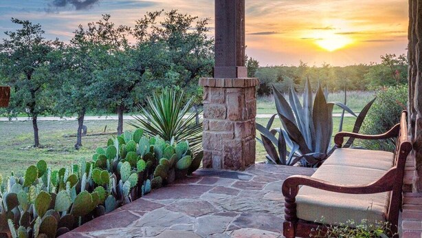 A patio with a stone bench, a stone pillar, and cacti. - Hill Country Escape-670 Heather Hills (Dripping Springs)
