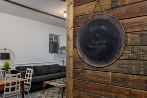 A rustic interior with a wooden wall, a blackboard sign, a sofa, a table, and chairs. - Historic Rumpel Kammer - Marktplatz Gem (Fredericksburg)