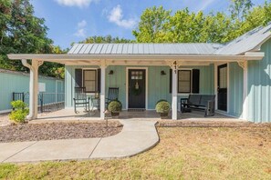 A light blue building with a porch, a front door, and a small garden area. - Town Creek Haus - Close to Wineries and Main! (Fredericksburg)