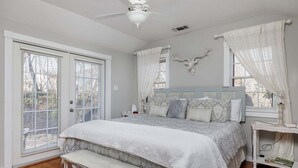 Una camera da letto con un letto, una panca, un comodino, una decorazione a testa di cervo appesa al muro e una ventola a soffitto.