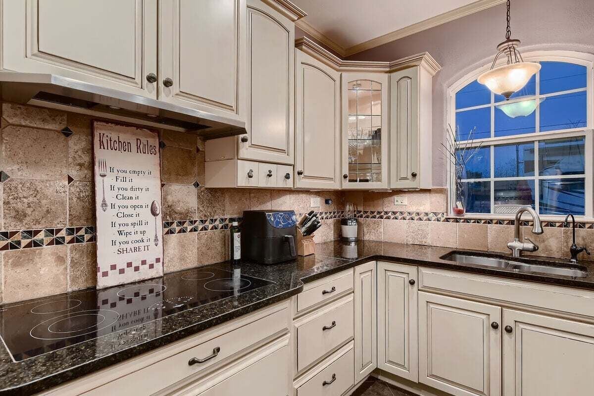 A kitchen with white cabinets, a black countertop, and a window with a view.
