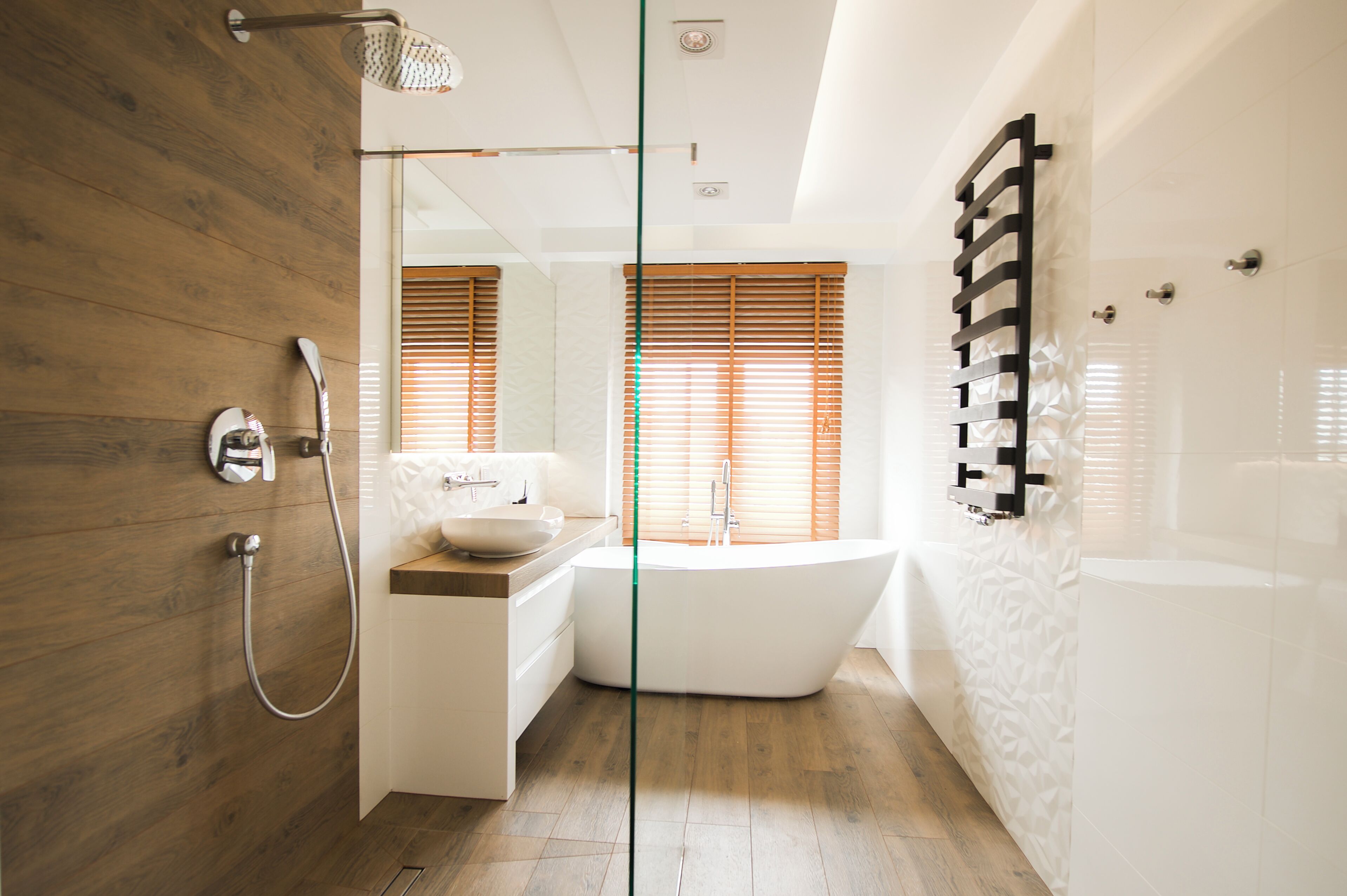 Ein modernes Badezimmer mit freitragender Badewanne, einer Duschkabine aus Glas und Holzboden.