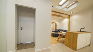 Una cocina moderna con una isla de madera, un comedor con mesa y sillas, y una puerta visible que conduce a otra habitación.