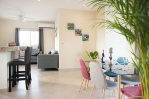 Ein modernes Wohnzimmer mit Essbereich, ausgestattet mit einem Deckenventilator, einer Couch, einem Couchtisch und einem Esstisch für sechs Personen.