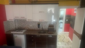 Una cocina compacta con lavavajillas integrado, microondas y un refrigerador pequeño.