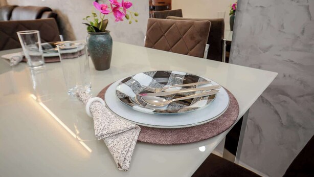 A dining table with a checkered plate, cutlery, a glass, and a napkin. - Casa Confortavel e Completa em Bariri (Bariri)