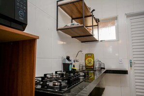Ett kök med en gasspis, en kaffemaskin och en hylla som hänger på väggen.