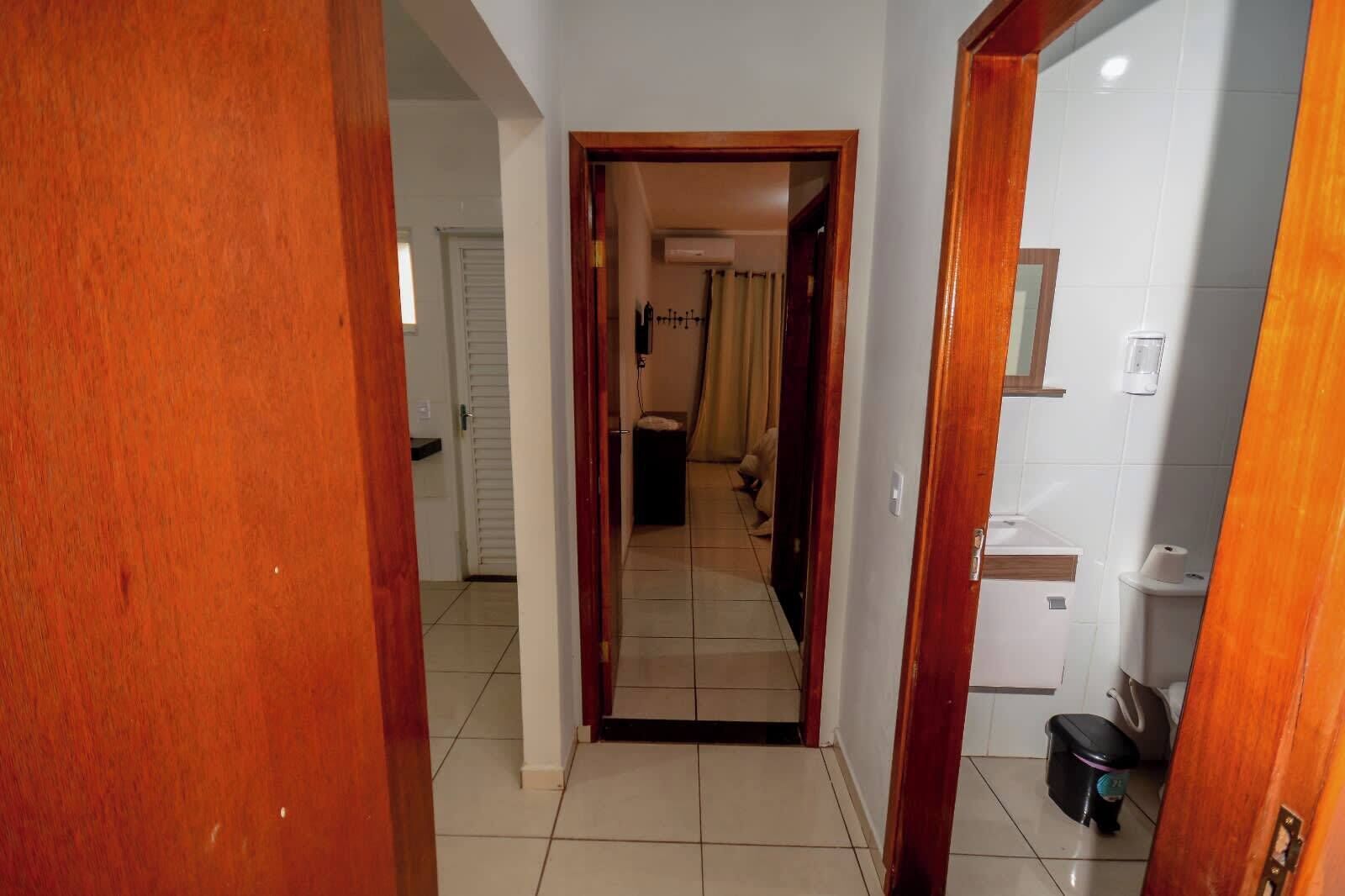 A hallway leading to a bathroom with a toilet, sink, and shower area.