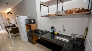 A modern kitchen with a gas stove, a microwave, and a coffee machine. - Casa Confortavel e Completa em Bariri (Bariri)