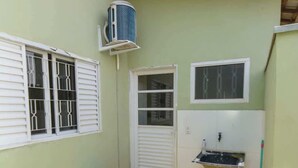 Ein kleiner, abgegrenzter Außenbereich mit Fenster, Tür, Spüle, Mülleimer und Gasflasche.