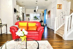 Una sala de estar con un sofá rojo, una mesa de centro de vidrio y un jarrón con flores.