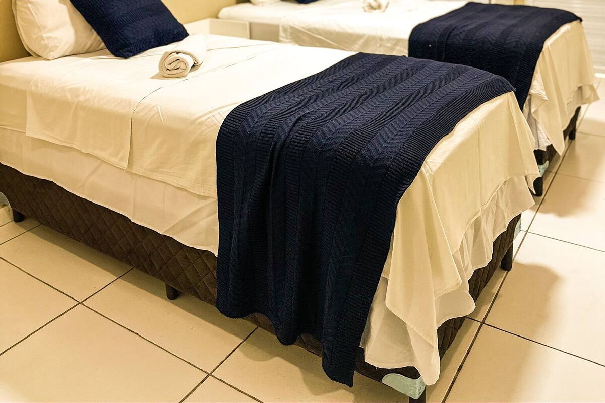 Een hotelkamer met twee bedden, een bureau en drie ingelijste kunstwerken aan de muur.
