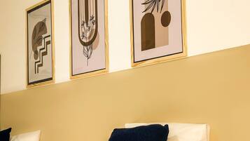 Quarto de hotel com uma cama, duas almofadas e três obras de arte emolduradas na parede.
