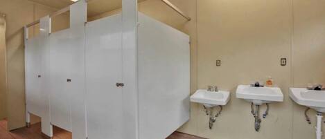 A public restroom with multiple stalls, a row of sinks, and a wooden floor.
