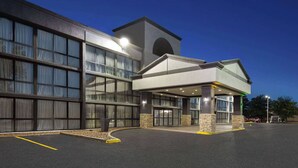 Um hotel moderno com fachada de vidro ampla, entrada coberta e base de pedra.
