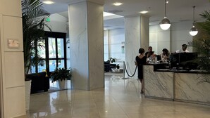 En rummelig lobby med marmorkolonner, en receptionsdisk og et siddeområde med en sofa.