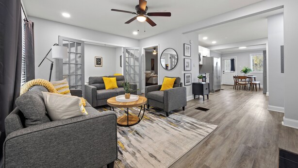 Un salon moderne avec un canapé, des fauteuils, une table basse et un ventilateur de plafond.