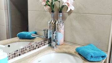 A bathroom with a white sink, two striped vases with flowers, a blue towel, and a mirror.