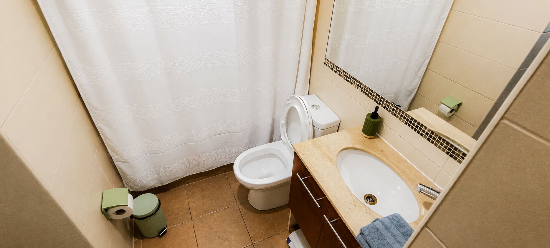 Un baño con inodoro, bidé, lavamanos y espejo.
