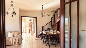 A dining area with a table set for four, a sofa, and a staircase. - ClickSardegna Villa Garden in Alghero for 10 Guests with Garden (Alghero)