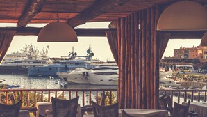 A restaurant with a view of a marina, wooden furniture, and hanging lamps. - ClickSardegna Villa Garden in Alghero for 10 Guests with Garden (Alghero)