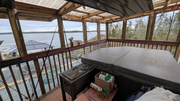 A wooden deck with a large mattress, a small table, and a box of items.