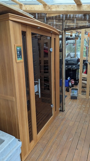 A wooden structure with a glass door, a control panel, and a grill area visible through the door.