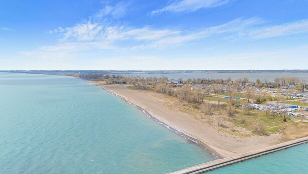 Una zona costera con playa, puerto deportivo y área residencial con casas y barcos.